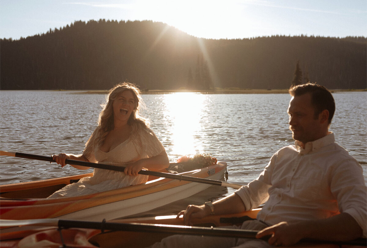 bride and groom laugh as they kayak in the alpenglow light at Sparks Lake in Bend, OR