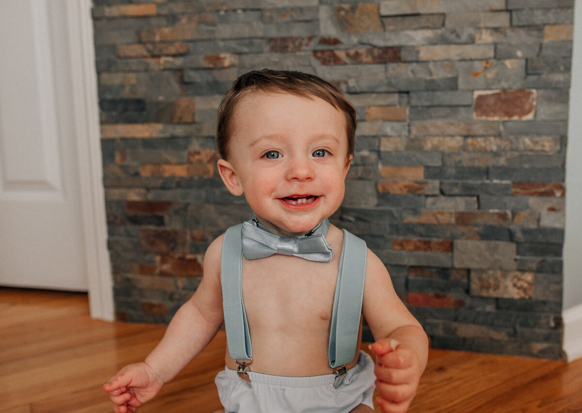Young baby wears a bow tie and smiles at the camera.