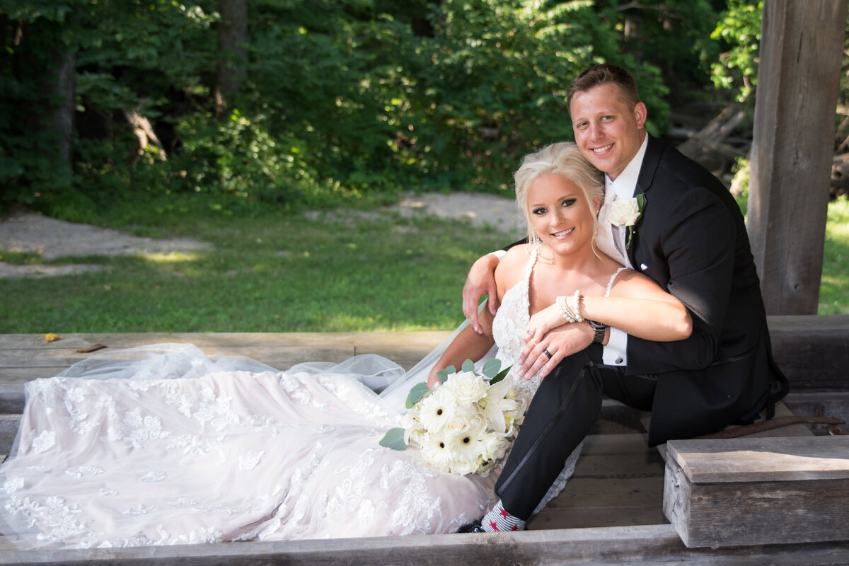 Bride and groom sit on outdoor stairs and smile
