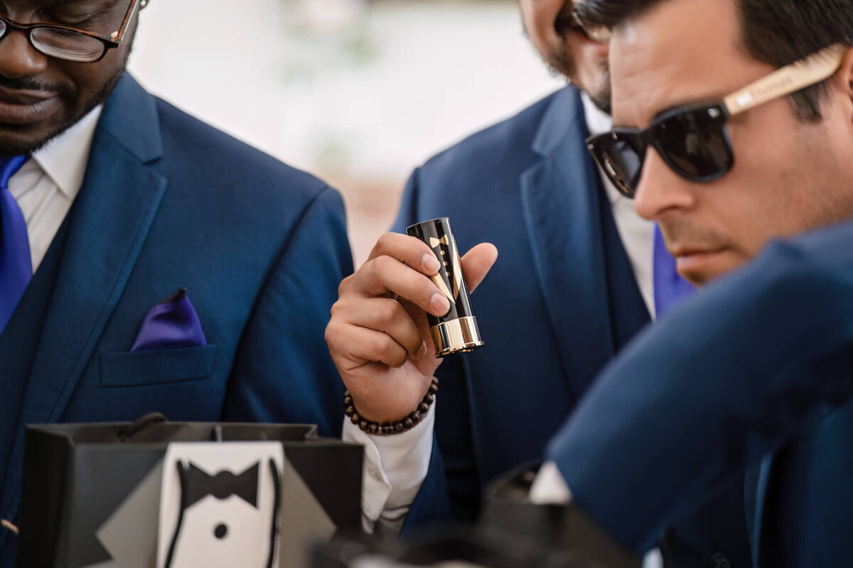 Stylish groom and groomsmen in navy suits adjusting cufflinks before the wedding ceremony.