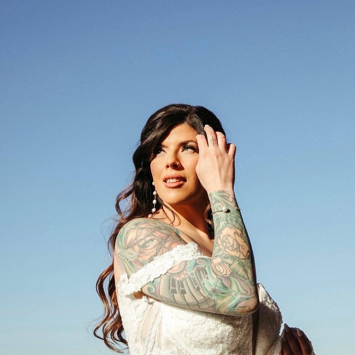 Bride in off-shoulder gown with long curled hair, styled for her wedding day in San Antonio by Mistique Makeup.