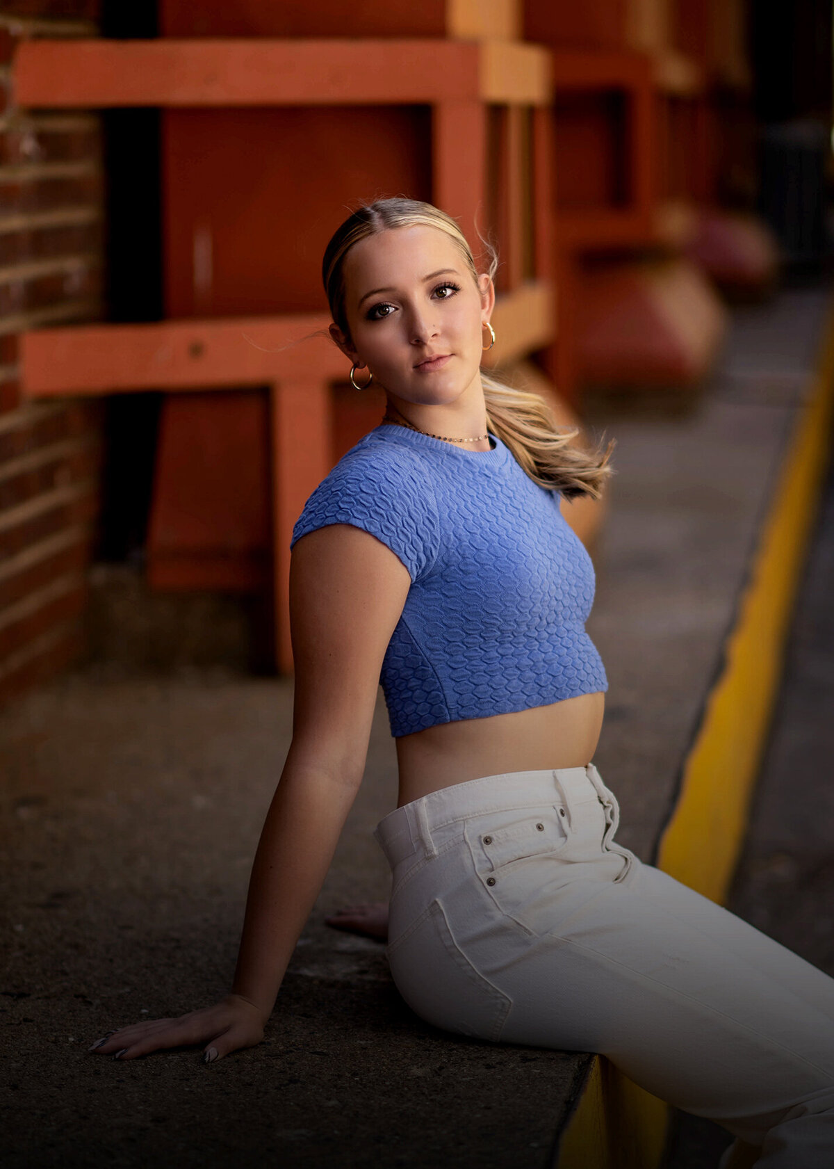 An image from a Pella Senior Photography session of a blonde girl leaning back on a loading dock