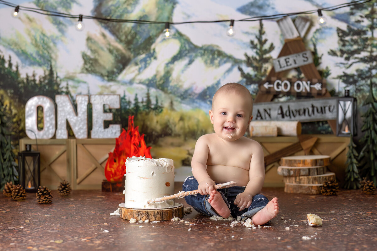 One year old Tampa baby enjoying a personalized luxury cake smash session with camping decorations