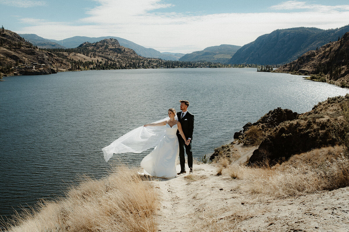 Bride and groom standing at the Kaleden lookout with the Skaha Lake below.
