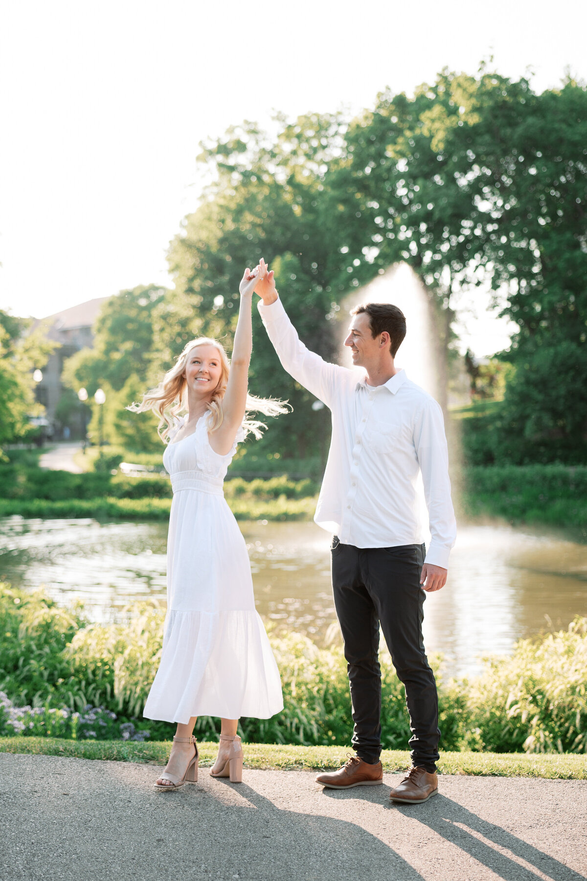 Couple dances near fountain in Columbus park, engagement session by Philly photographer.