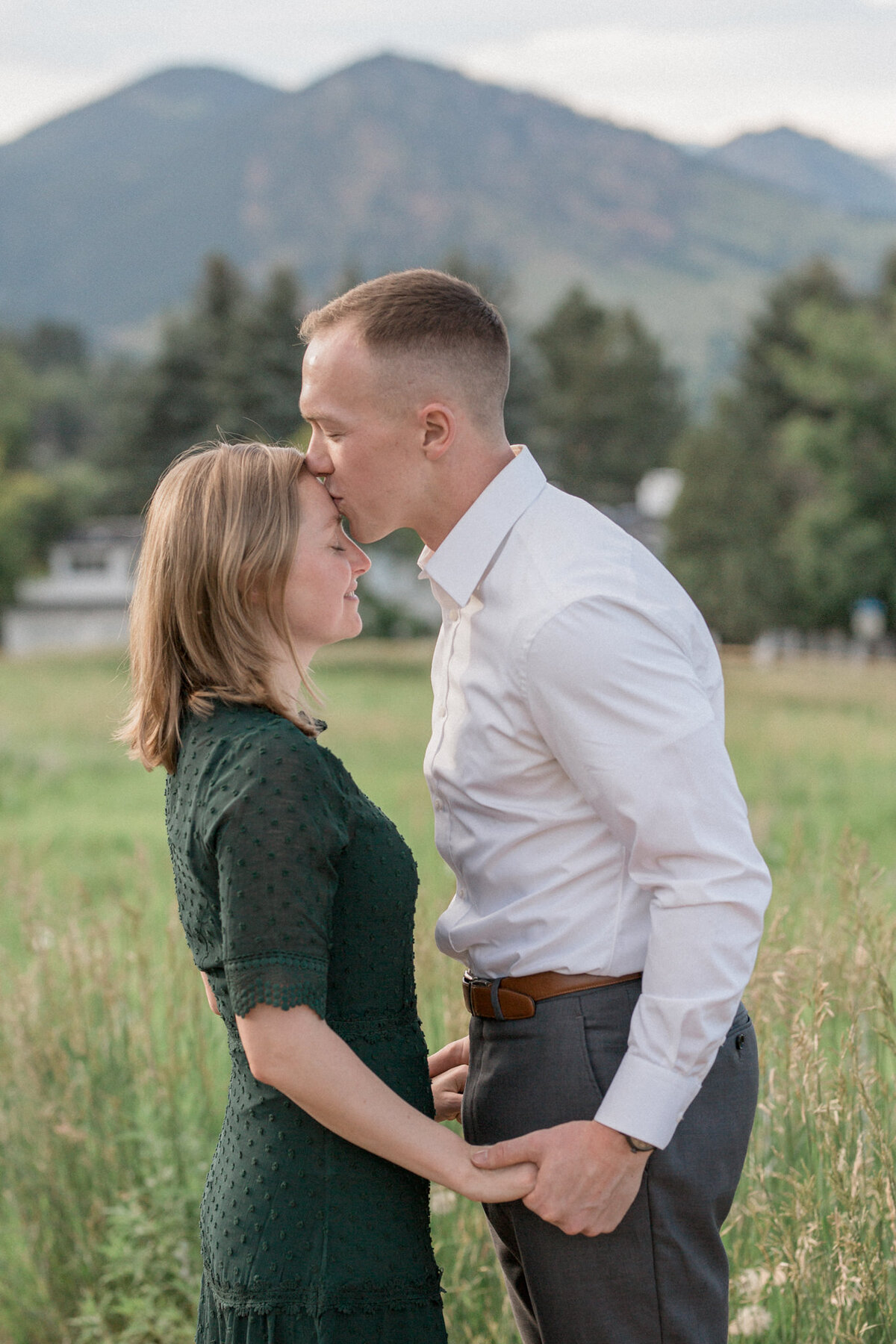 A couple joyfully poses for engagement photos against the scenic backdrop of  Boulder's skyline and mountains