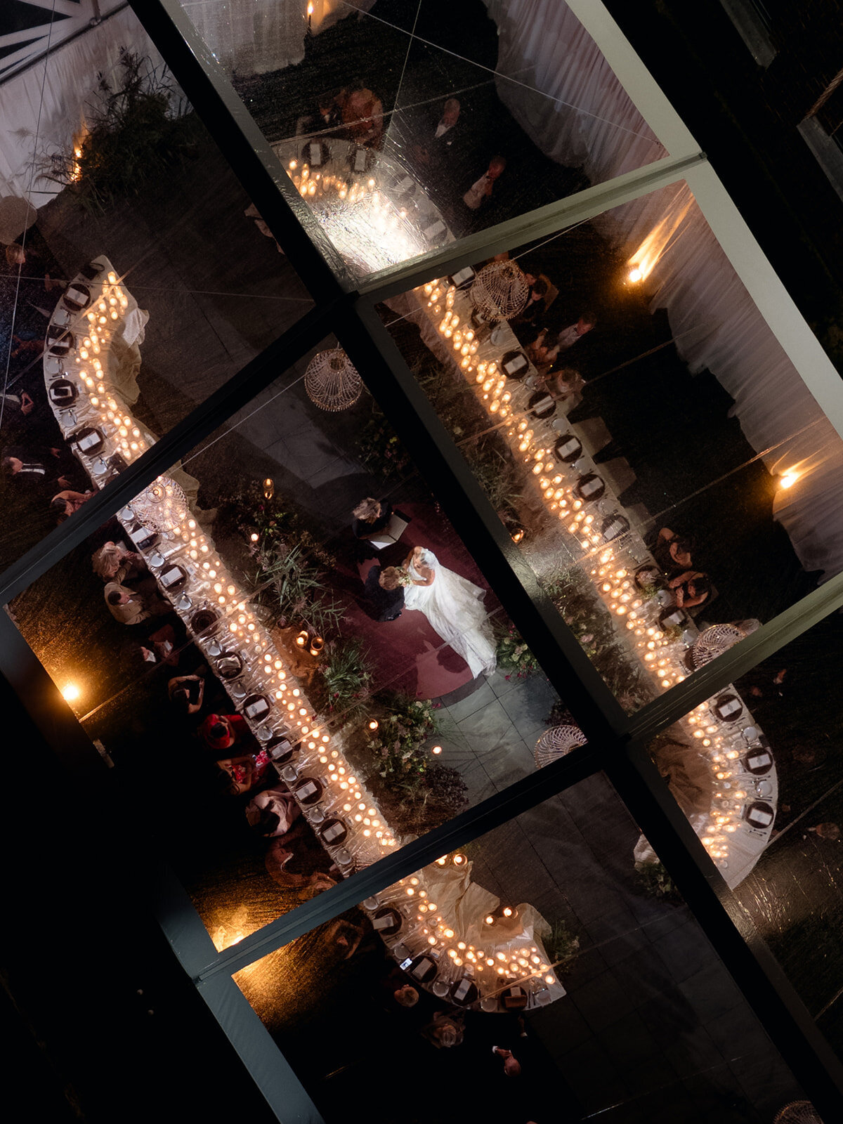 Aerial view through the clear tent roof of Aubri and Cody dancing between candlelit tables