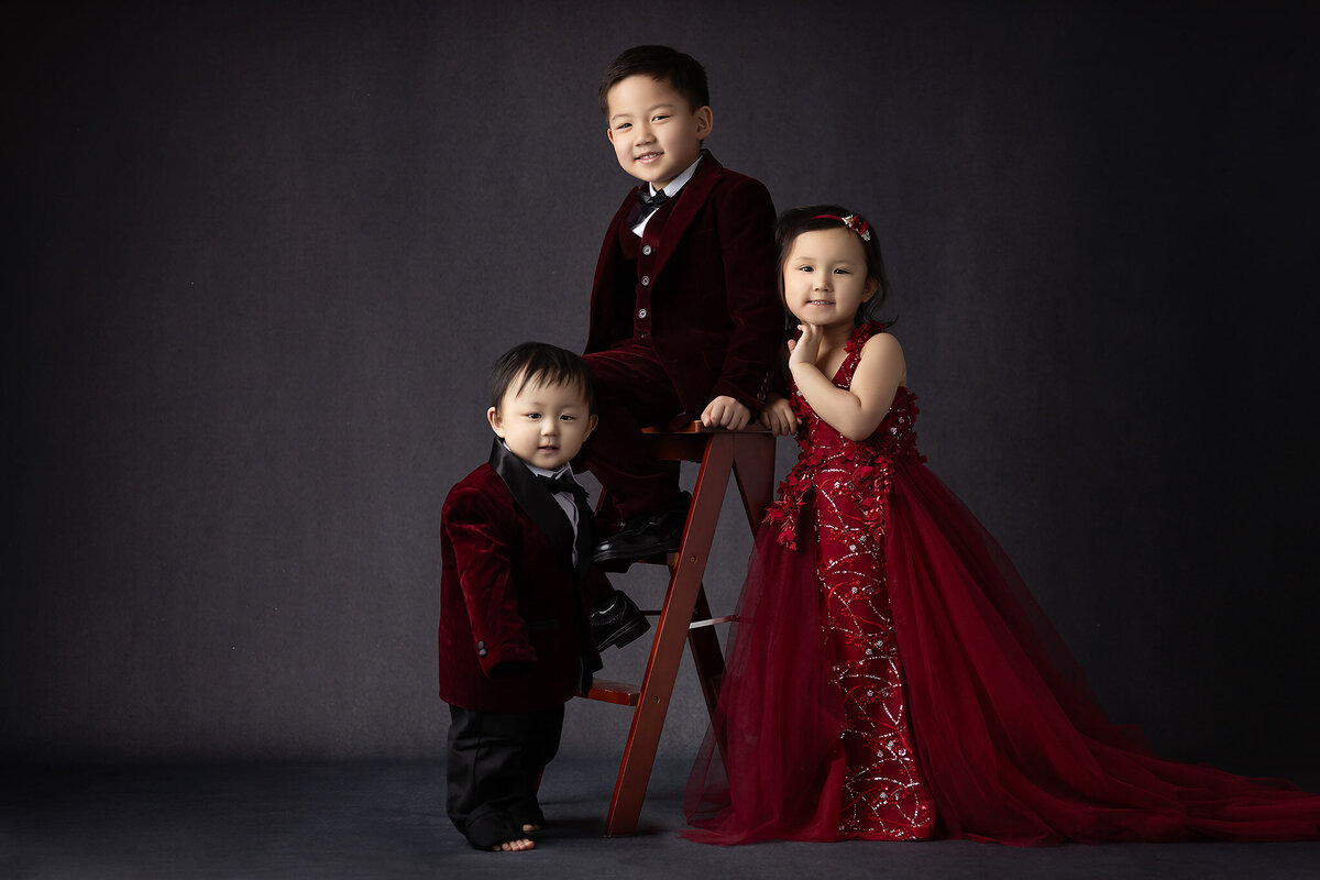 Dallas milestone photographer captures three siblings in velvet attire for a stylish family portrait.