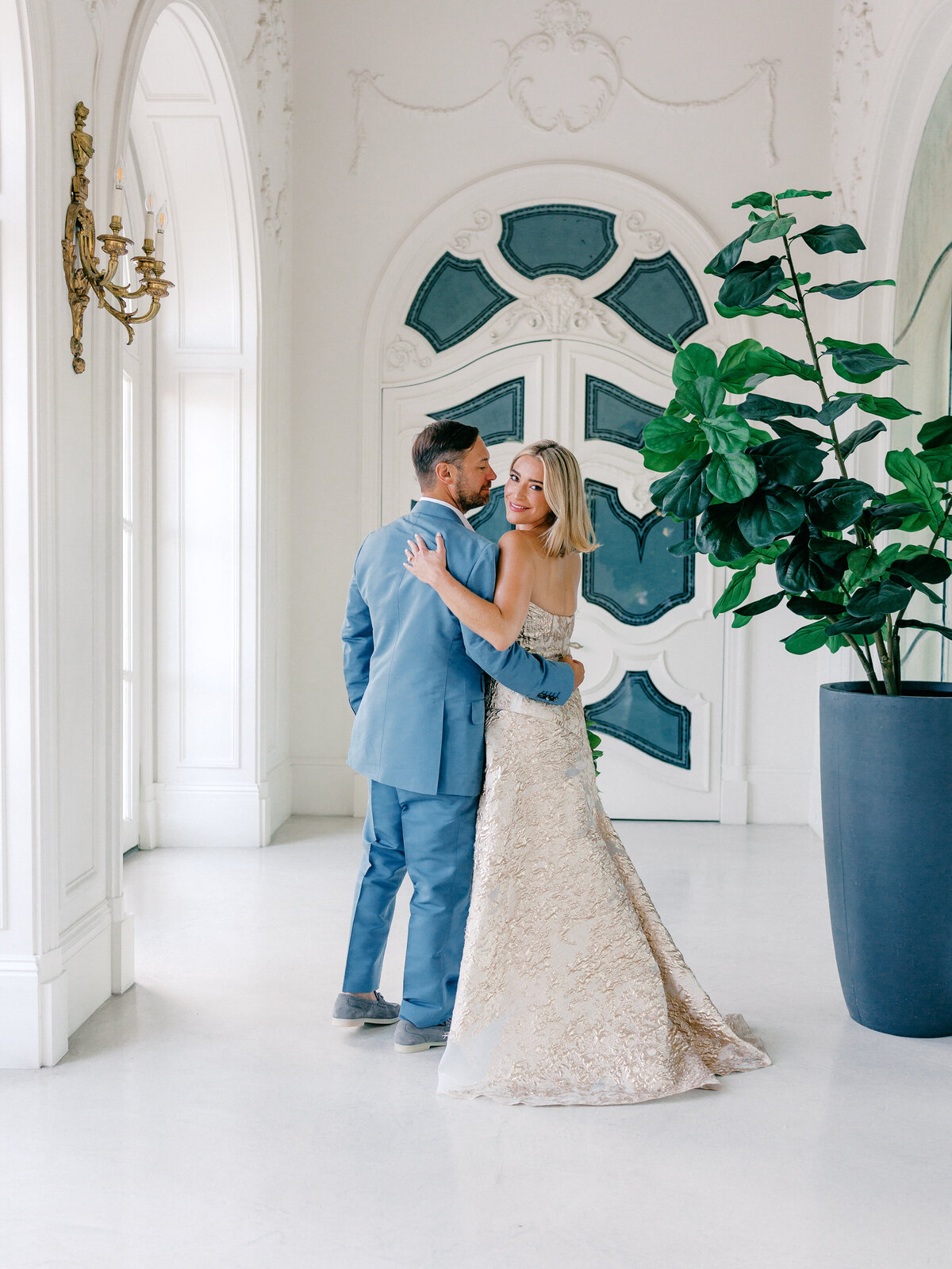 Bride and groom standing in an embrace in an estate hallway