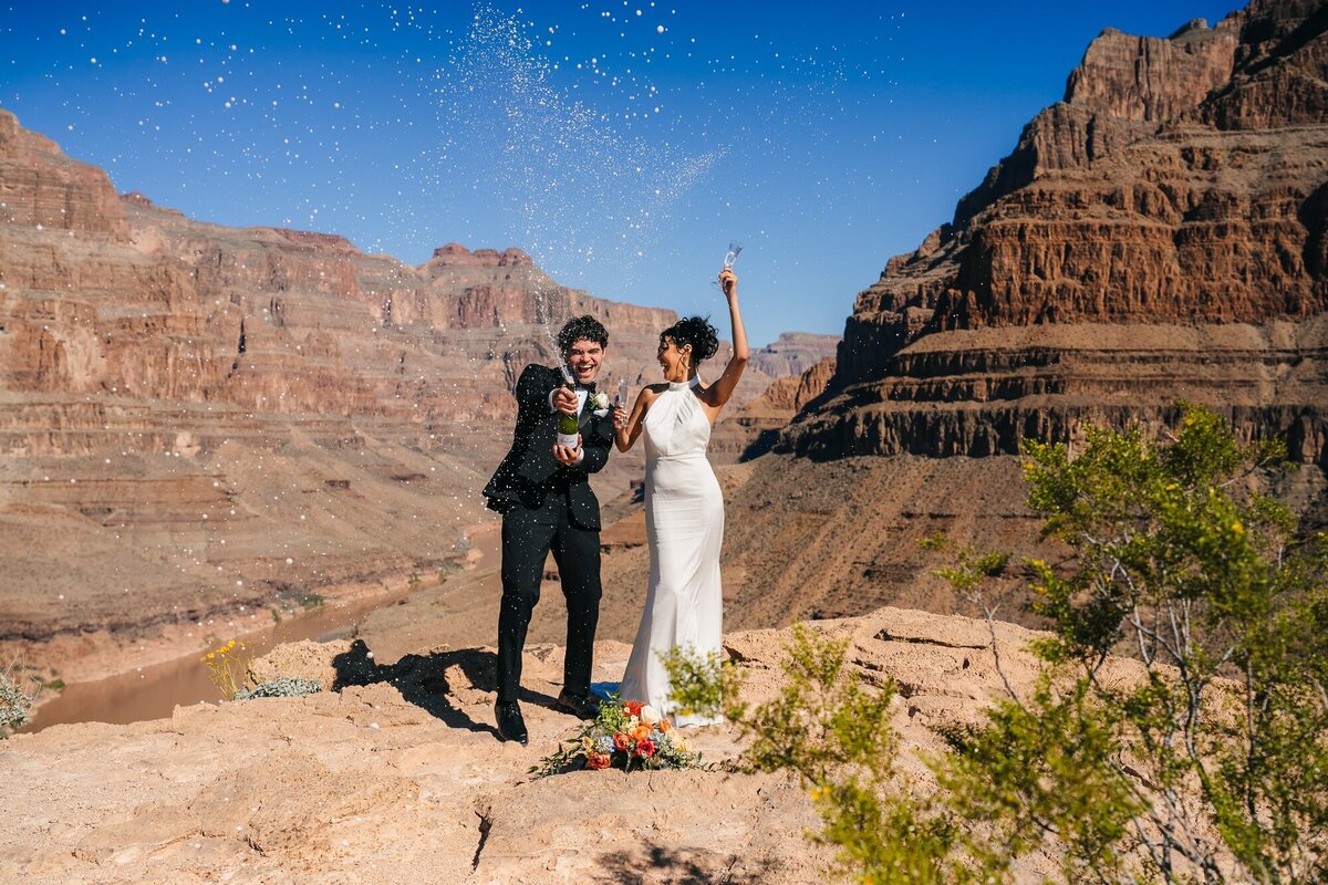 A couple popping their champagne while celebrating their elopement