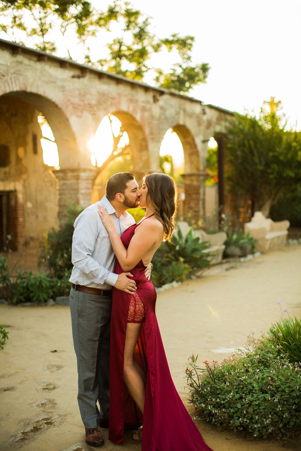 Engaged couple share a romantic kiss during a photo session at the Mission San Juan Capistrano