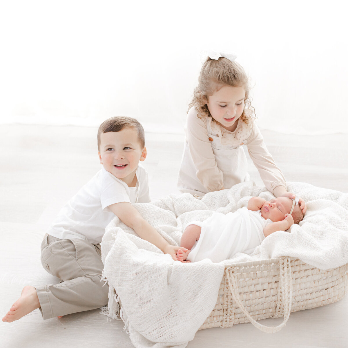big siblings look at newborn sister during photoshoot with boston newborn photographer