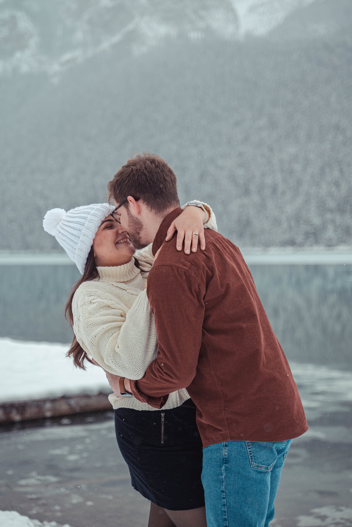 Candid snowy embrace near frozen lake in Banff.