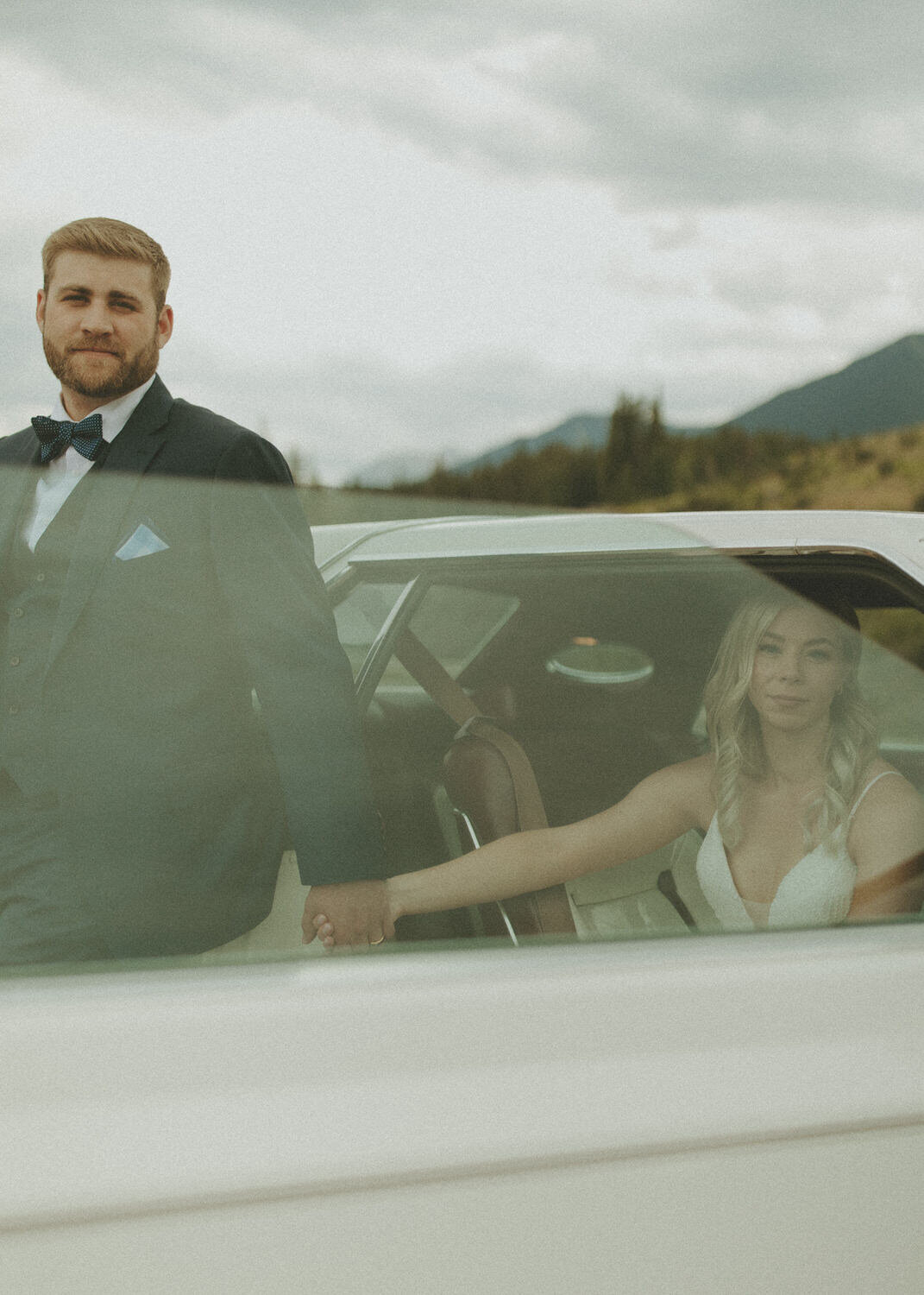 bride and groom holding hands while sitting in a vintage car