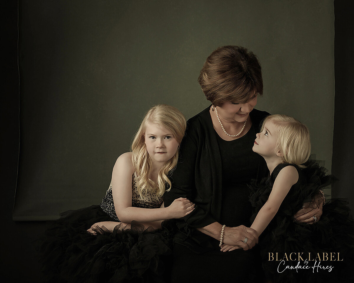 grandmother photographed with two granddaughters black label style on layered black canvases