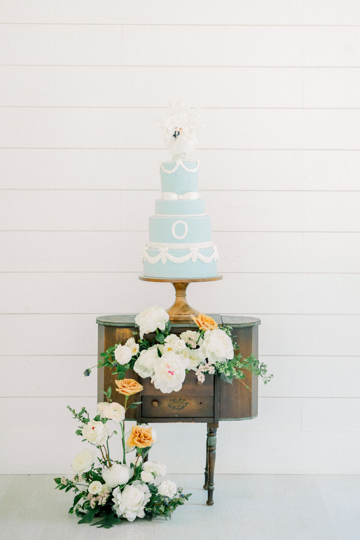 Stunning luxury wedding details of the reception cake with florals surrounding it