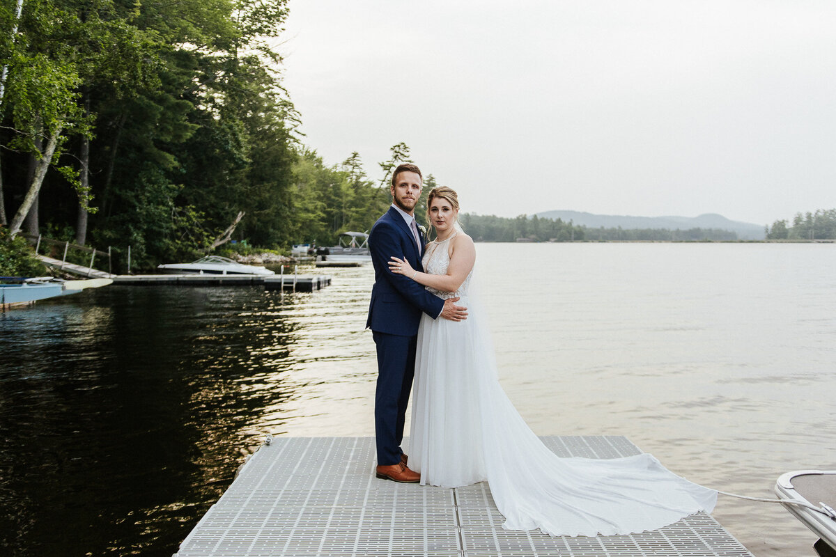 Couple taking an editorial portrait on the dock of the brides grandfathers property in Maine 