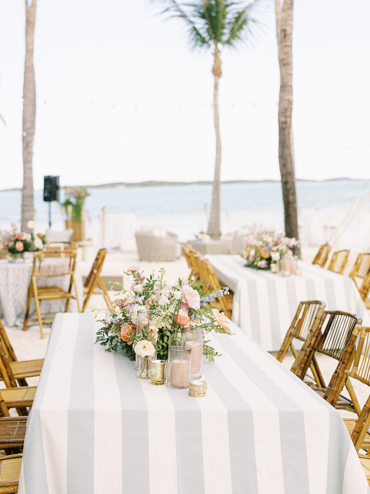 Tropical table floral meadows consisting of orchids, and roses in peach, pink, dusty blue, pale yellow, orange, and green tones. Exuma, Bahamas destination wedding reception tropical floral design. Spring beach wedding floral design by Rosemary & Finch Floral Design.