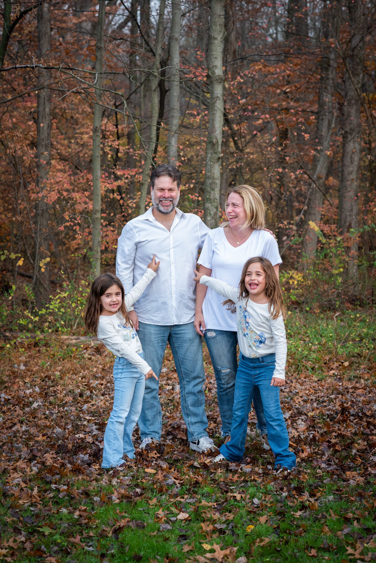 Two parents laughing with their daughters standing in front of them