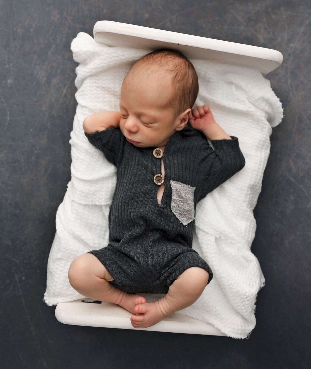Newborn photo of a baby boy laying in a bed in an Erie Pa photography studio