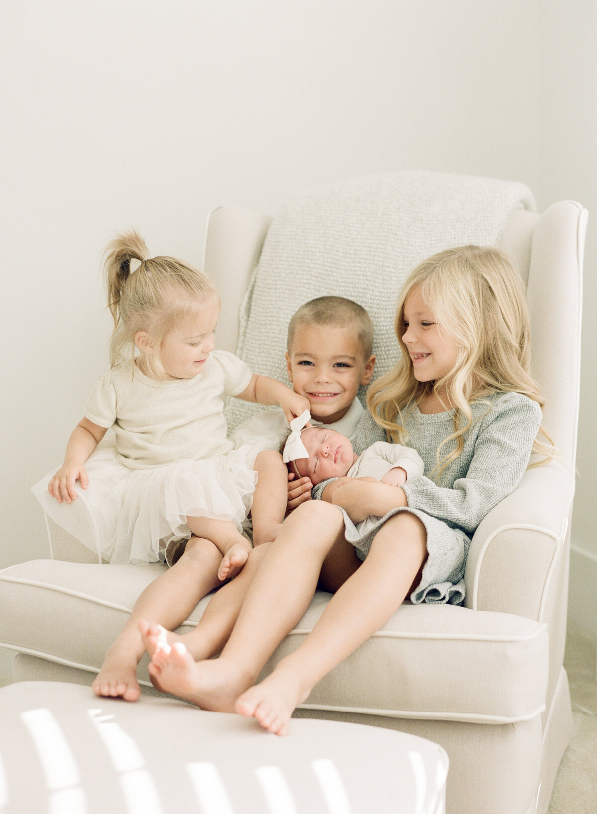 Big siblings snuggle their little sister during a newborn session. Image by Raleigh newborn photographer A.J. Dunlap Photography.