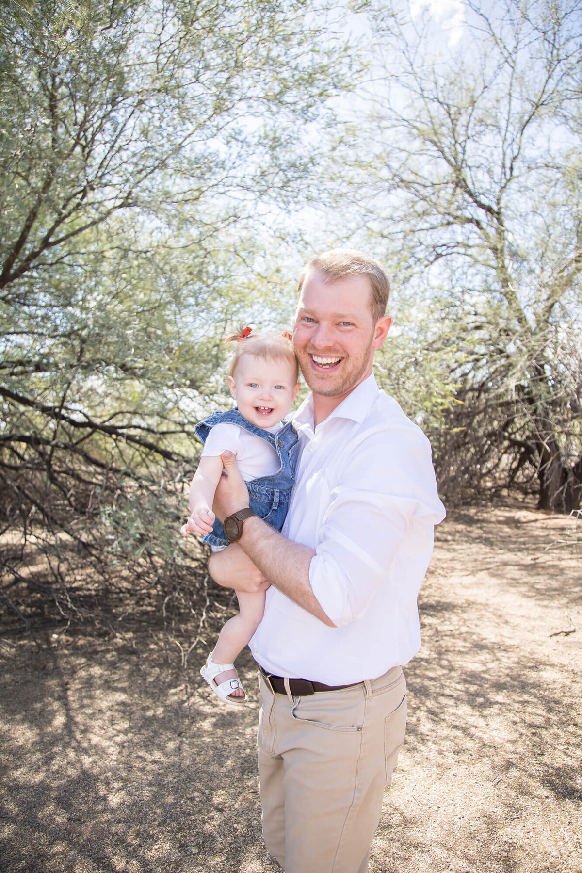 Happy toddler in father's arms in desert park at midday