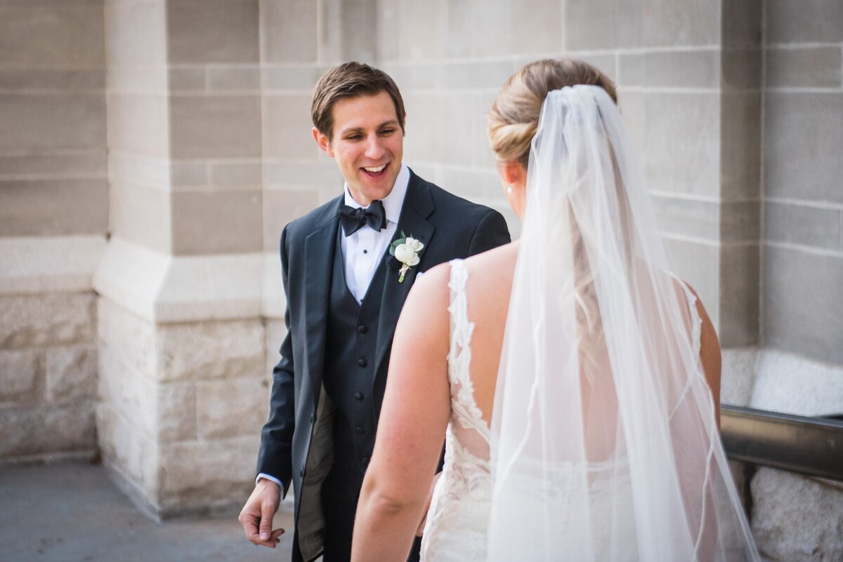 A groom reacts with a smile as he sees his bride during their first look.