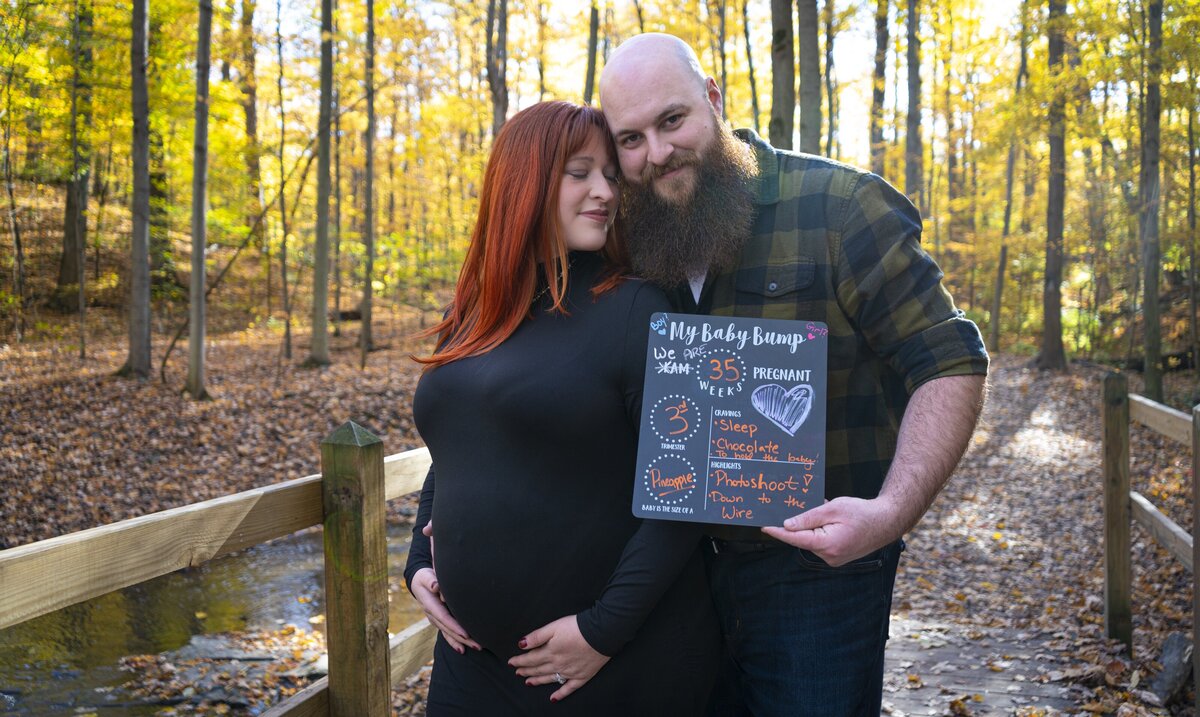 Photo of soon-to-be parents holding each other with a chalkboard for their maternity progress