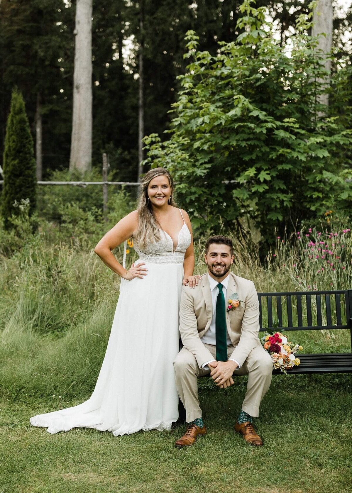 Bride and groom smiling and her bouquet rests on the bench.
