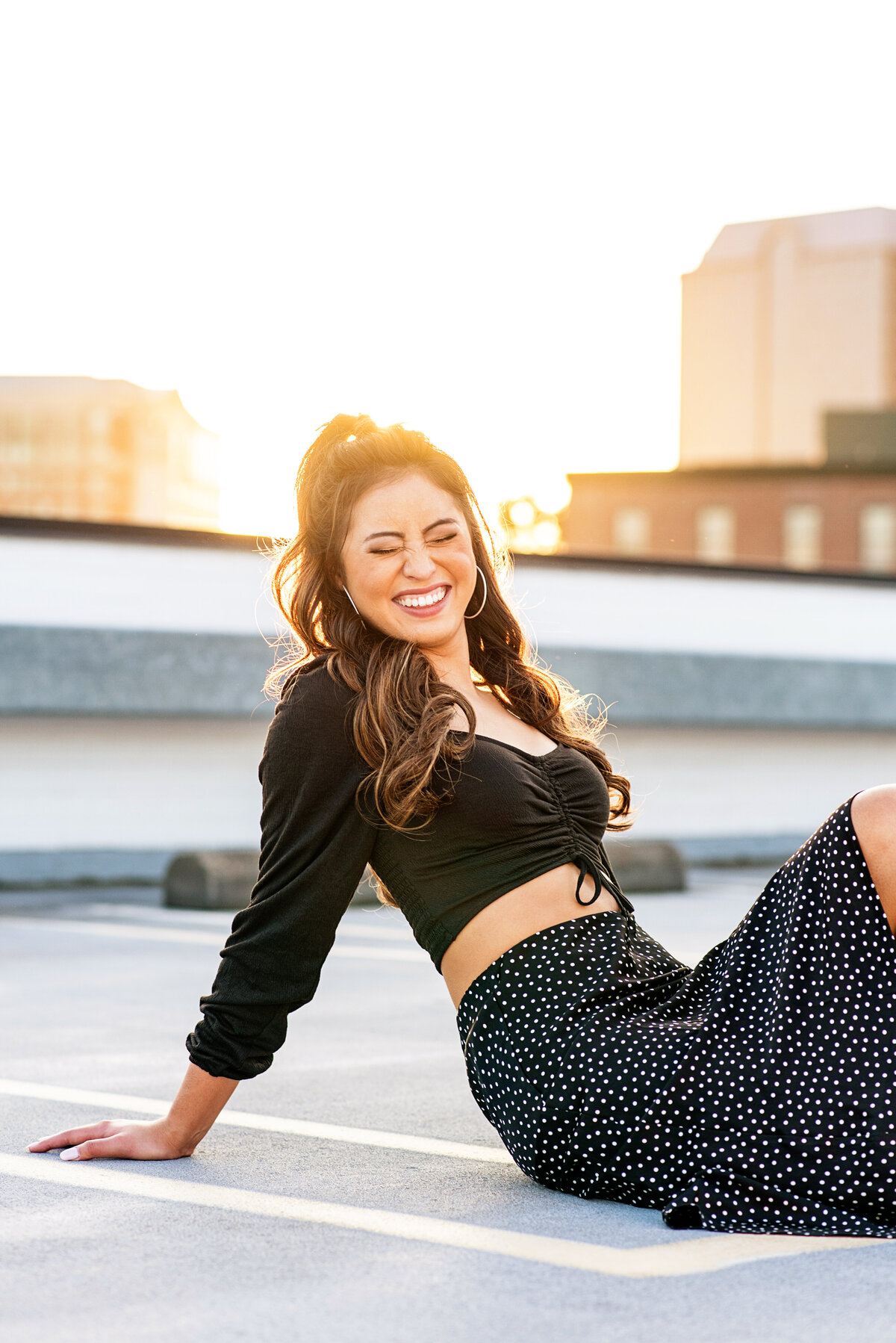 Senior girl laughing on rooftop with eyes closed.