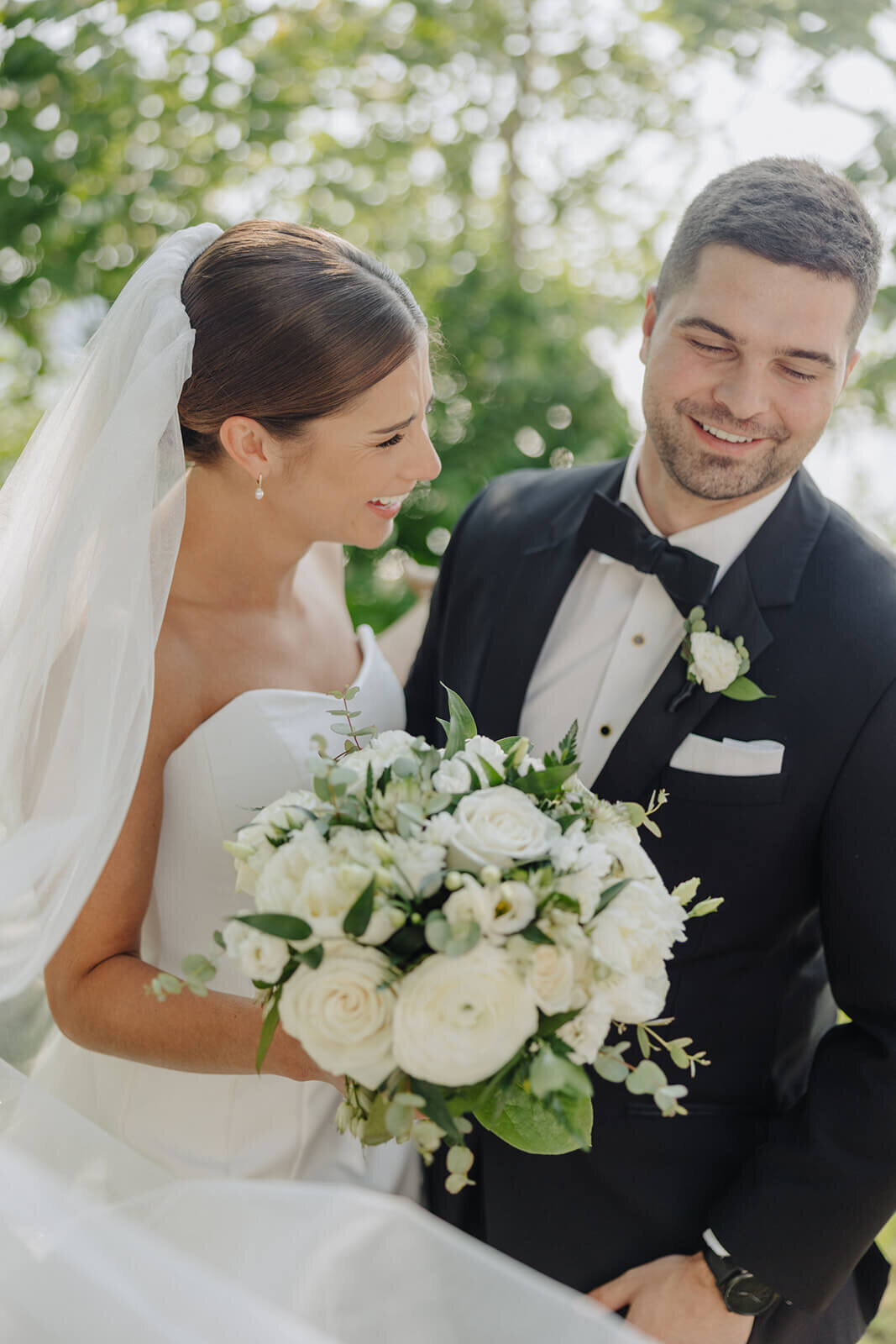 Bride holding white bouquet of florals with groom at Canandaigua Country Club wedding, NY