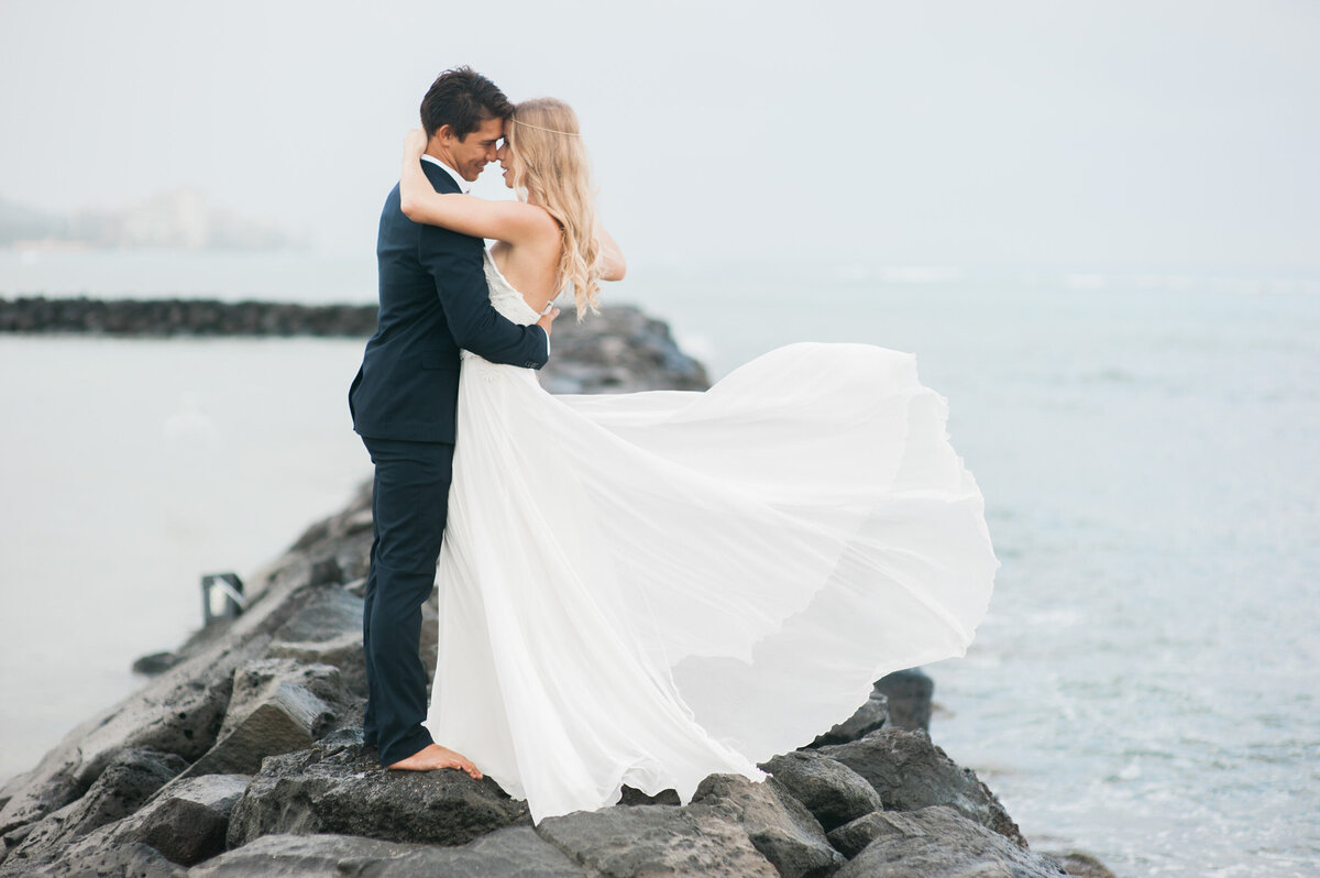 wedding photos on the waikiki beach rock pier with biracial couple