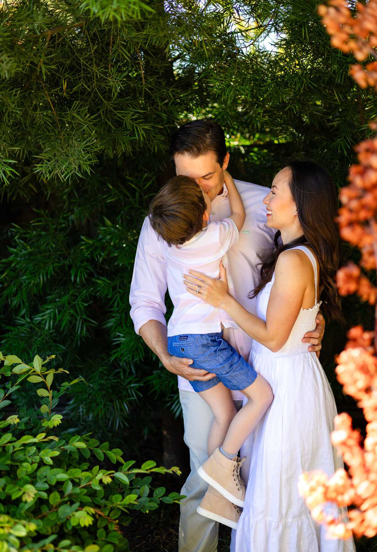 Parents holding son while embracing in sunlit garden, Bay Area Family Portfolio – Ellobelle Photography