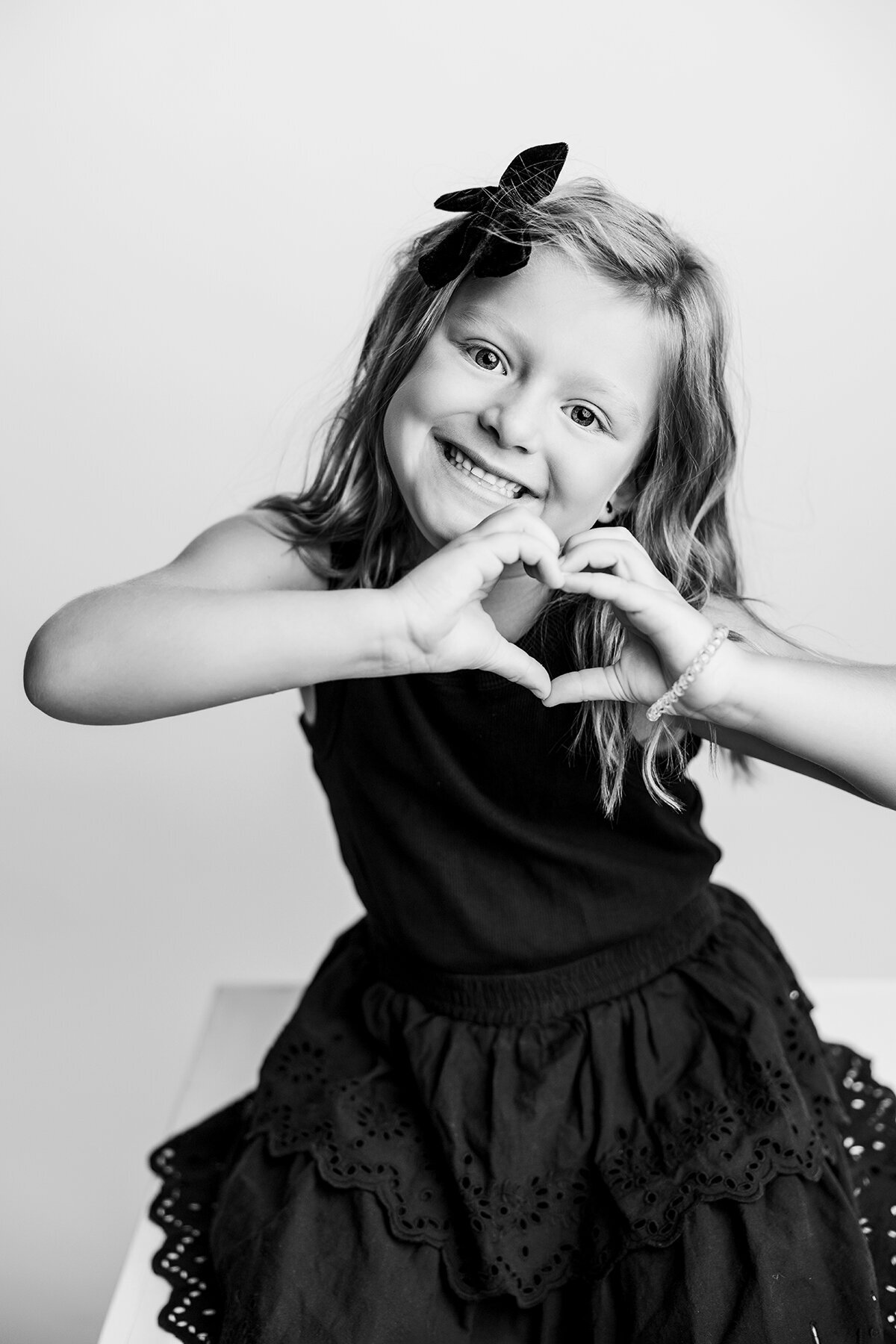 Little girl in Fort Collins, CO making a heart with her hands while smiling