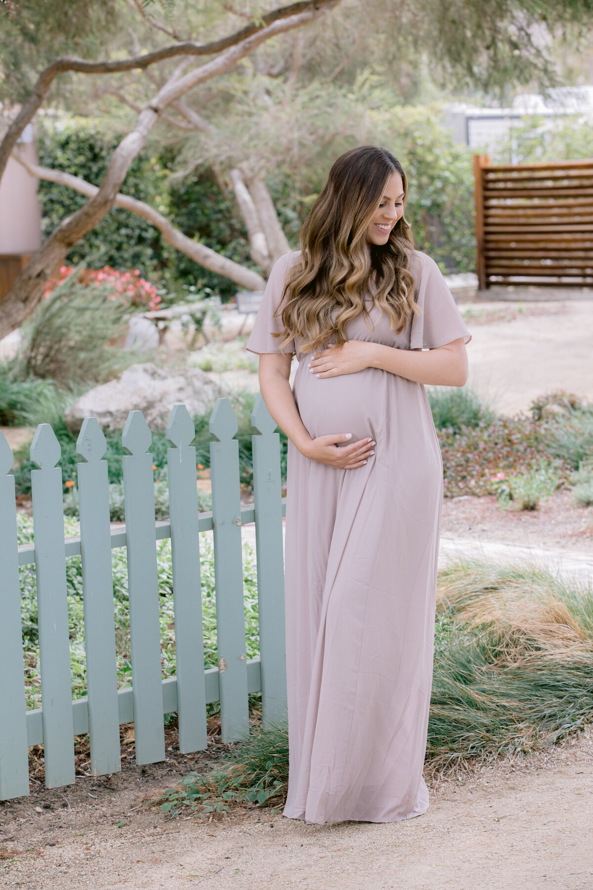 A woman holding her baby bump and smiling
