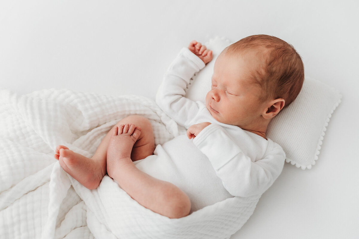 newborn baby boy sleeping on white blanket by Denver newborn photographer