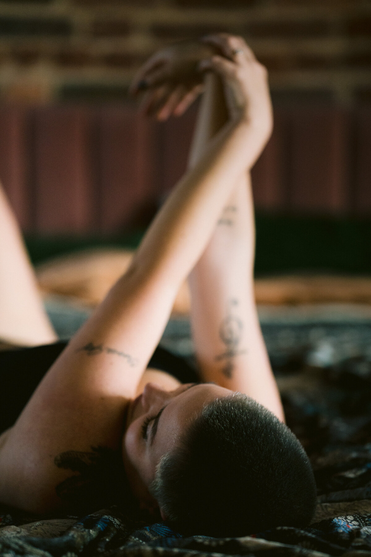 A person laying in bed with their arms stretched above them.