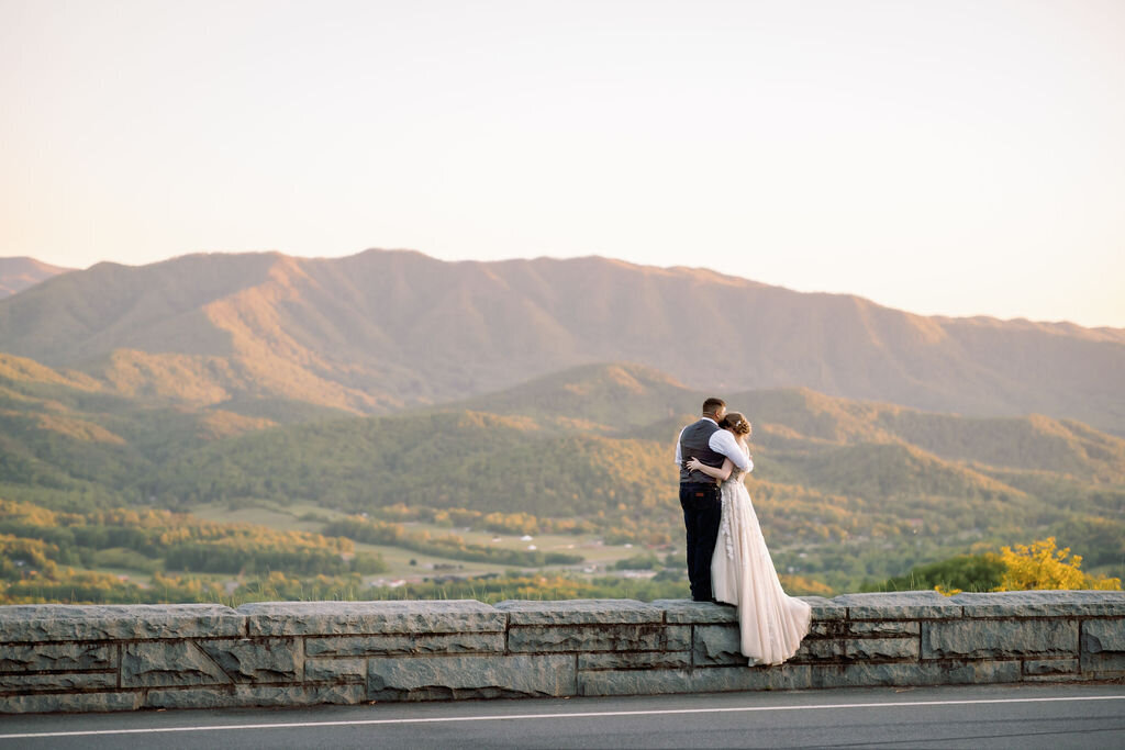 couple eloping to Gatlinburg with bride and groom hugging each other on foothills parkway overlook at sunset