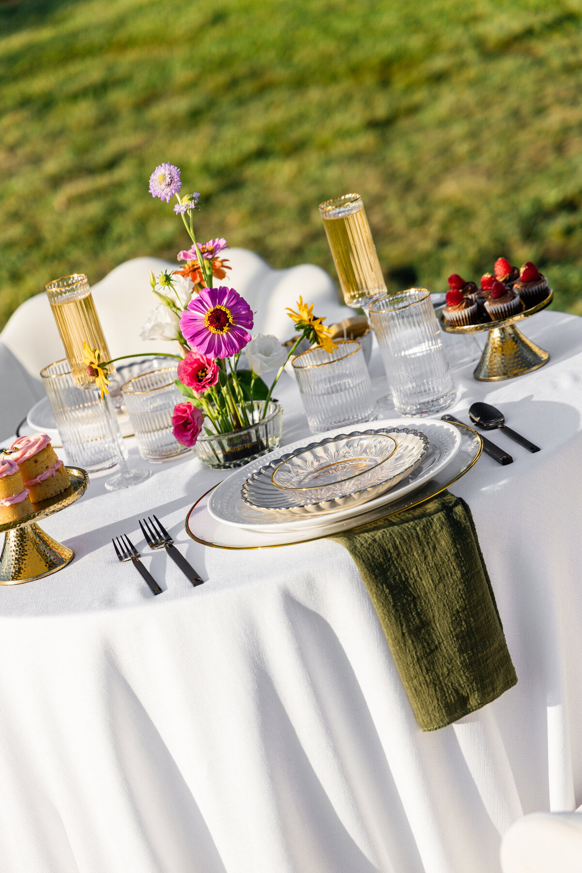 pink orange and white flowers on white table cloth with mixed metal place setting and mini chocolate and vanilla cupcakes