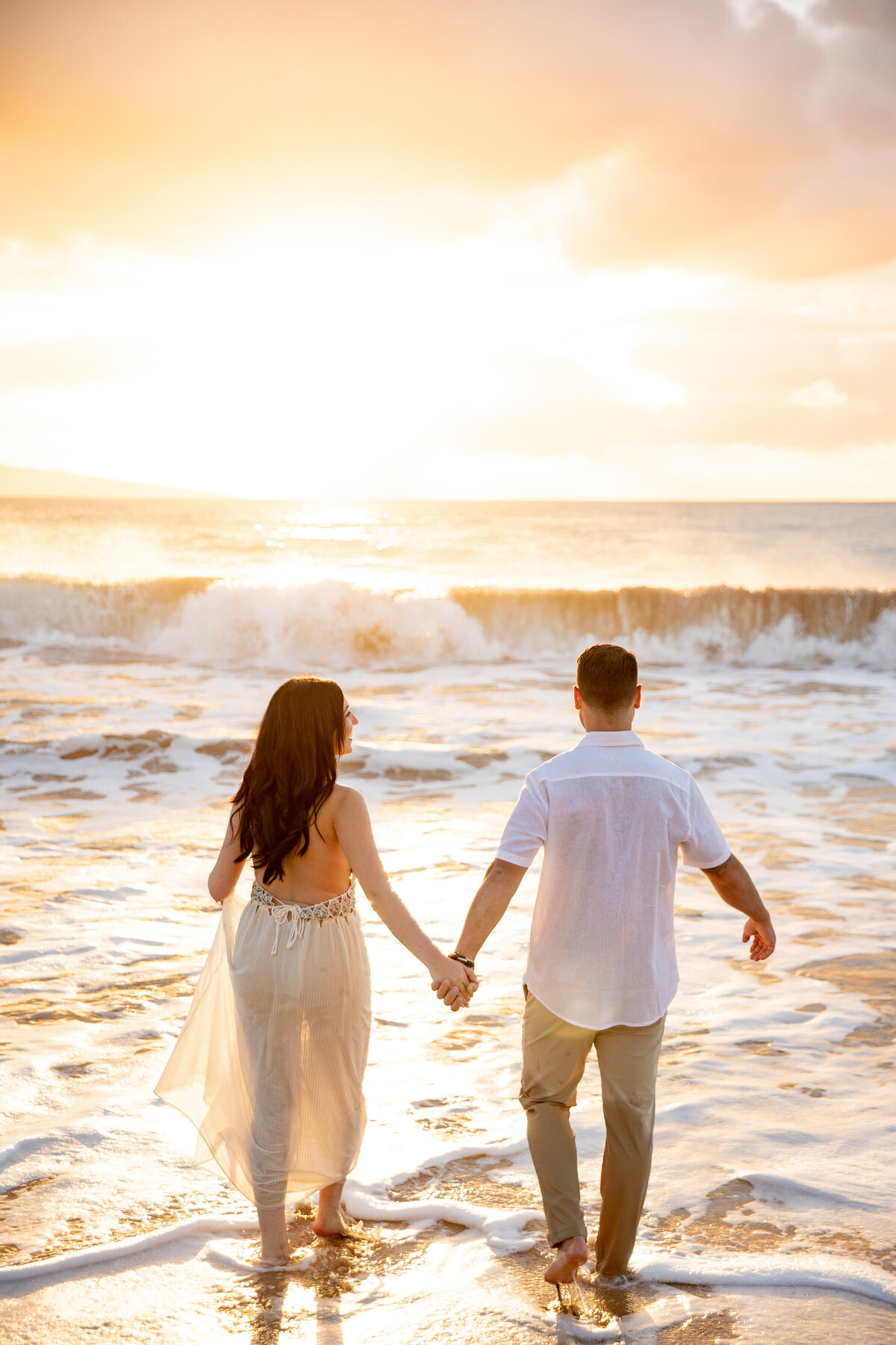 Maui couples Photographer captures man and woman holding hands while walking into ocean