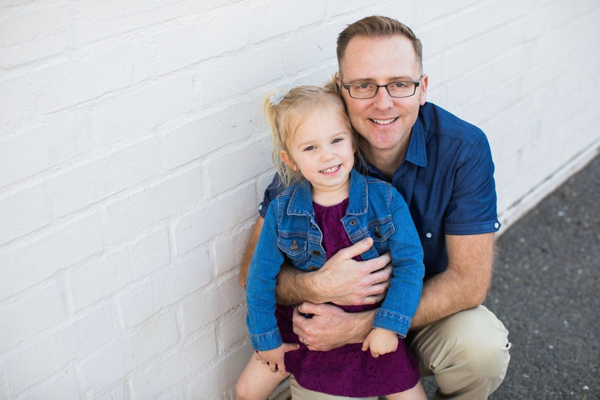 A father squats down and poses with his little girl for the photographer