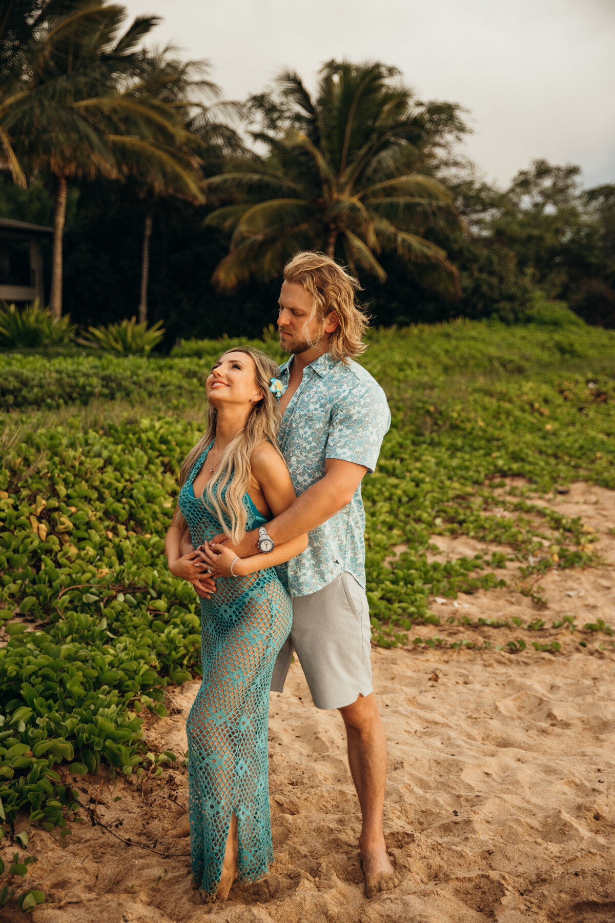 Hawaii Engagement Photographer captures woman laughing while man hugs her during beach engagement photos