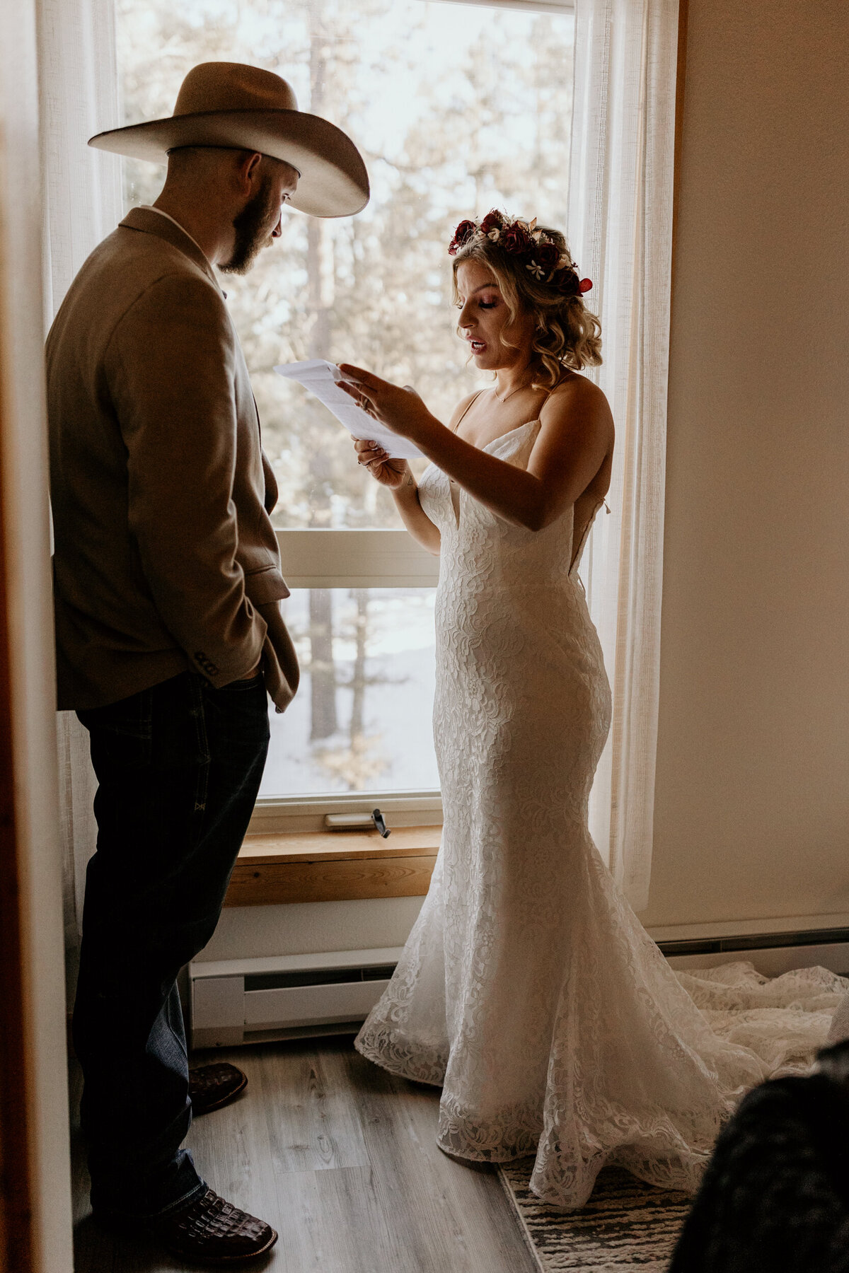 bride and groom exchanging personal vows in front of a window in a cabin