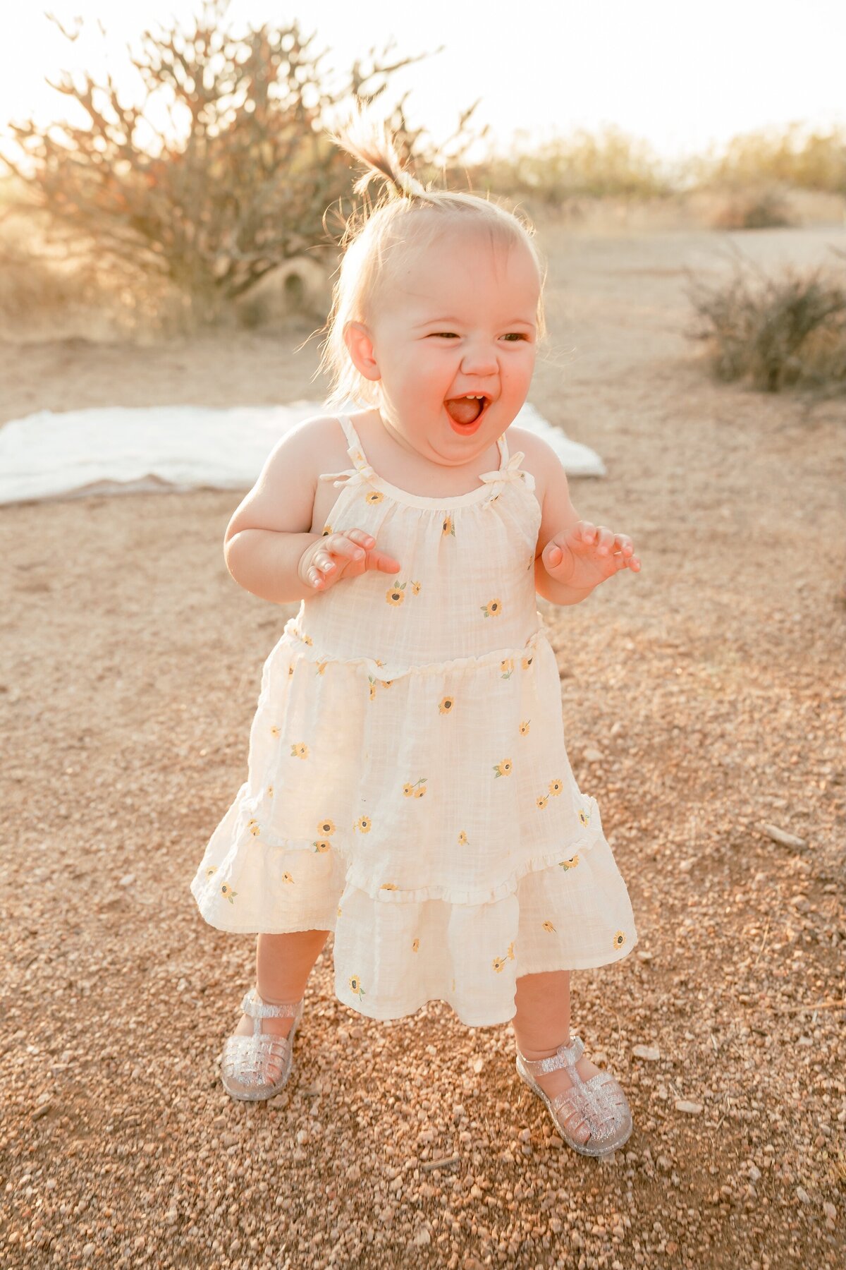 Little girl toddler walking in north scottsdale desert with big smile on face
