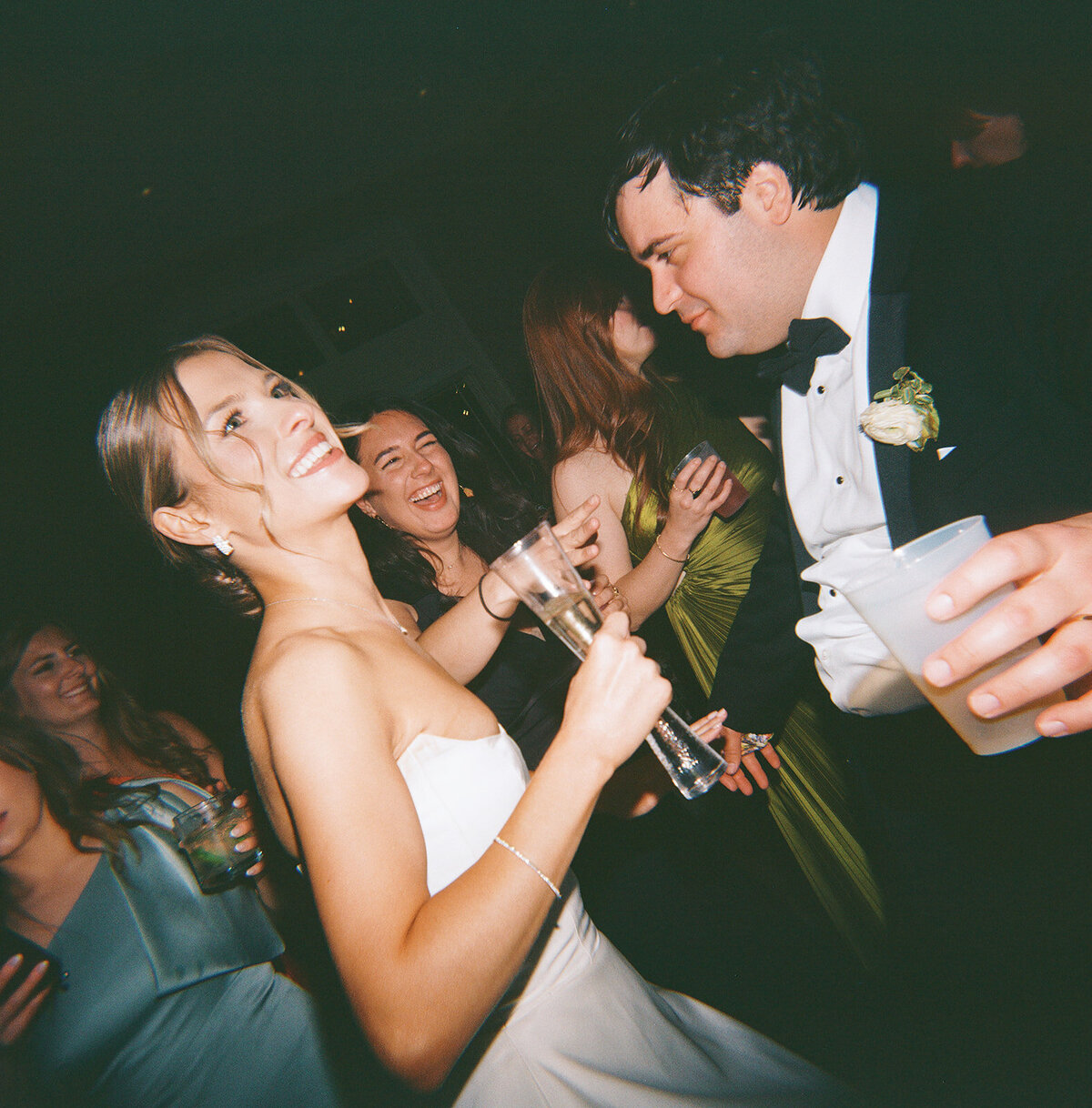 Bride and groom laughing and dancing together, surrounded by friends on the lively wedding reception dance floor at Burritt on the Mountain.