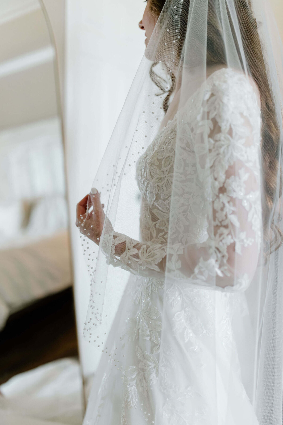 Harleton, TX bride looking into mirror after putting on wedding dress and veil before East Texas wedding ceremony