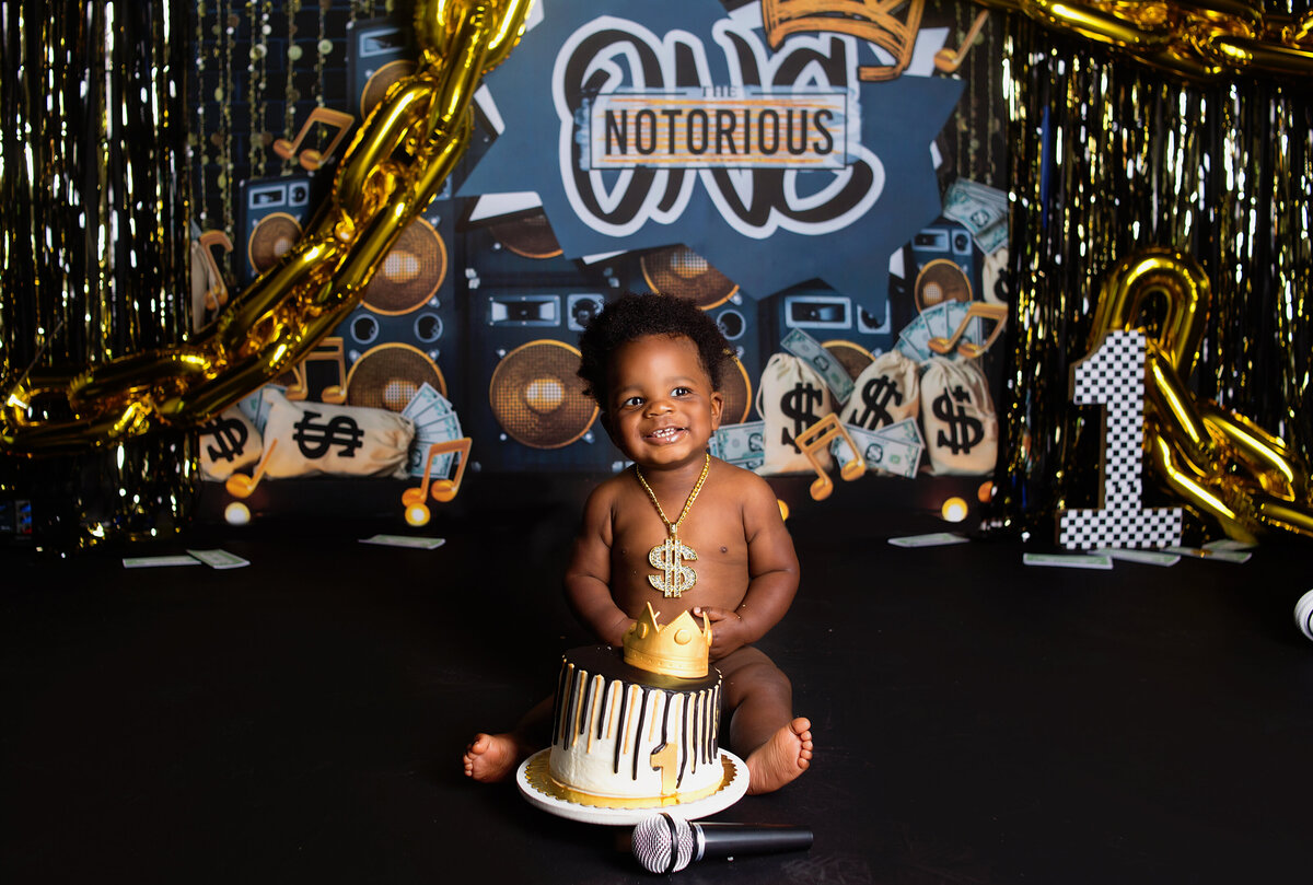 baby boy smiling sitting in front of a cake, during cake smash photoshoot with Franklin, Tennessee family photographer in Franklin, Tennessee photography studio
