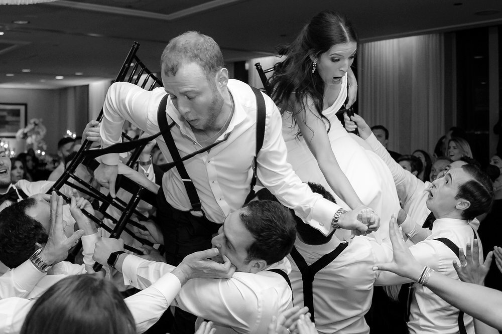couple falls from chairs during their wedding reception hora in Chicago