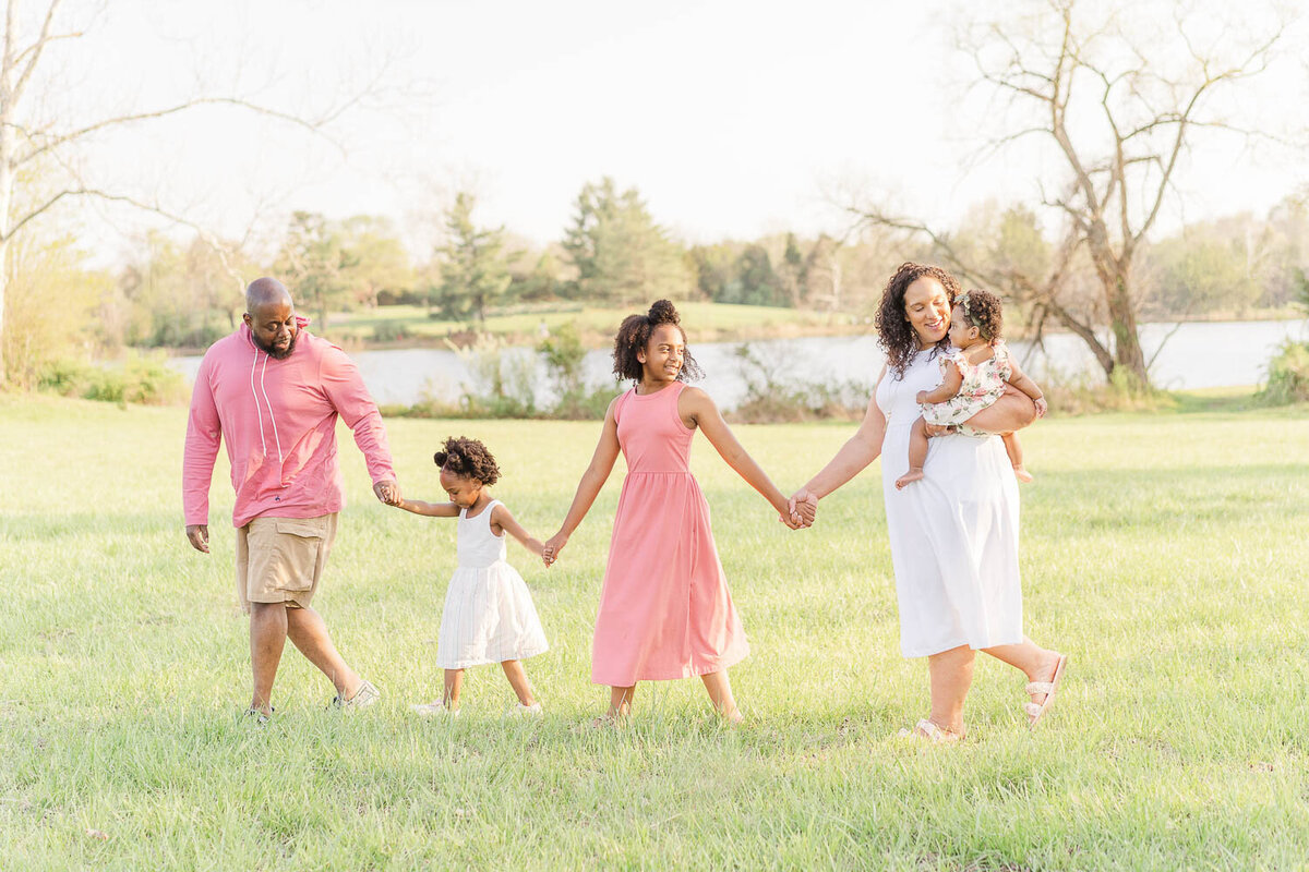 family of 5 holding hands walking led by dad during Reston, VA spring mini session