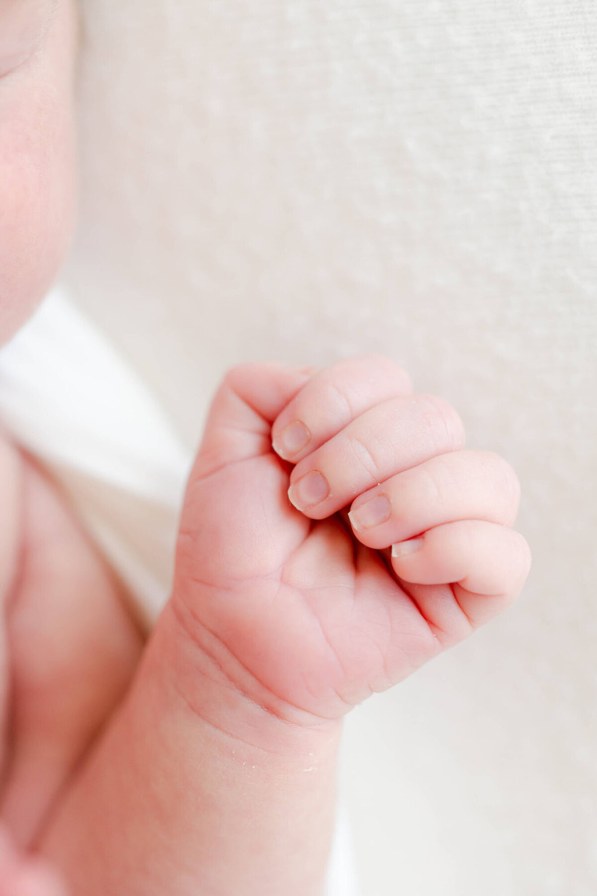 Soft natural light detail hand portrait by a newborn photographer Bay Area, baby sleeping on bed.
